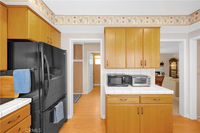 2006 W 180th Pl, Torrance, CA 90504 - kitchen with black appliances, tile countertops, light wood-style flooring, and decorative backsplash