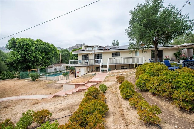 23328 Valley Circle Blvd, Chatsworth, CA 91311 - rear view of house with solar panels, a wooden deck, an outdoor pool, and stucco siding