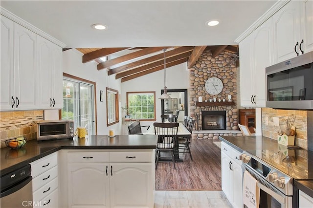 23328 Valley Circle Blvd, Chatsworth, CA 91311 - kitchen featuring stainless steel appliances, dark countertops, a peninsula, a fireplace, and white cabinetry