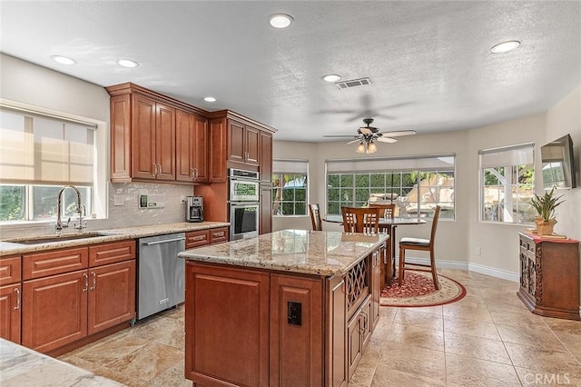 1459 W Quince Ct, Ontario, CA 91762 - kitchen with stainless steel appliances, a sink, baseboards, a ceiling fan, and light stone countertops