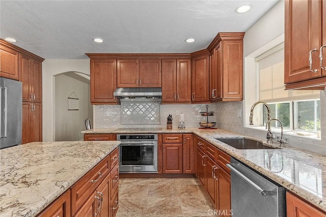 1459 W Quince Ct, Ontario, CA 91762 - kitchen with stainless steel appliances, a sink, under cabinet range hood, backsplash, and arched walkways