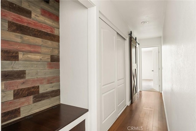 16481 Valle Vista Way, Riverside, CA 92506 - corridor featuring a barn door, wooden walls, dark wood finished floors, and baseboards