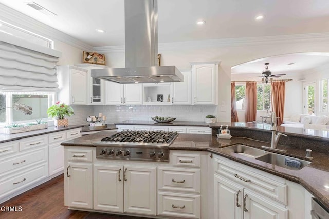 3007 Springbank Ct, Bakersfield, CA 93311 - kitchen featuring island exhaust hood, stainless steel appliances, arched walkways, dark stone counters, and ornamental molding