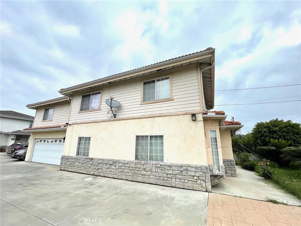 3717 Durfee Ave, El Monte, CA 91732 - view of front of home with stucco siding, stone siding, a garage, and driveway