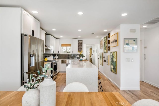 4852 W 129th St, Hawthorne, CA 90250 - kitchen featuring stainless steel appliances, under cabinet range hood, white cabinets, recessed lighting, and backsplash