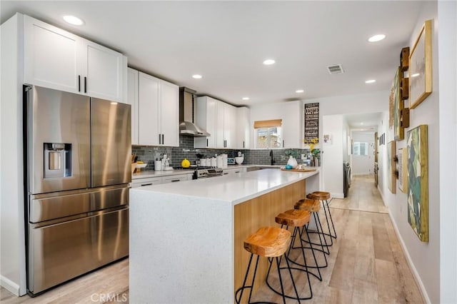 4852 W 129th St, Hawthorne, CA 90250 - kitchen featuring stainless steel appliances, wall chimney exhaust hood, a breakfast bar area, white cabinets, and light countertops