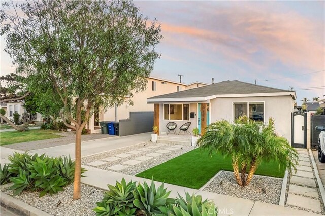 4852 W 129th St, Hawthorne, CA 90250 - rear view of house with stucco siding, concrete driveway, a shingled roof, a yard, and a porch