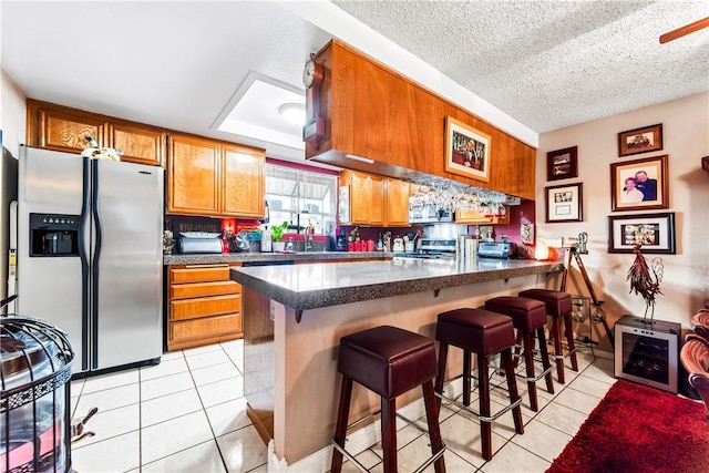 5471 E Centralia St Unit 24, Long Beach, CA 90808 - kitchen with stainless steel refrigerator with ice dispenser, brown cabinets, light tile patterned floors, a peninsula, and a textured ceiling