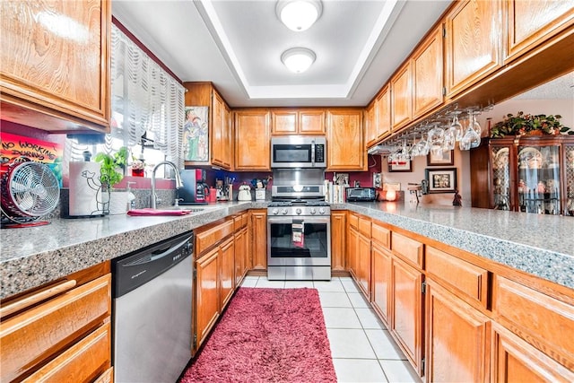 5471 E Centralia St Unit 24, Long Beach, CA 90808 - kitchen with appliances with stainless steel finishes, a sink, light tile patterned flooring, a tray ceiling, and brown cabinetry