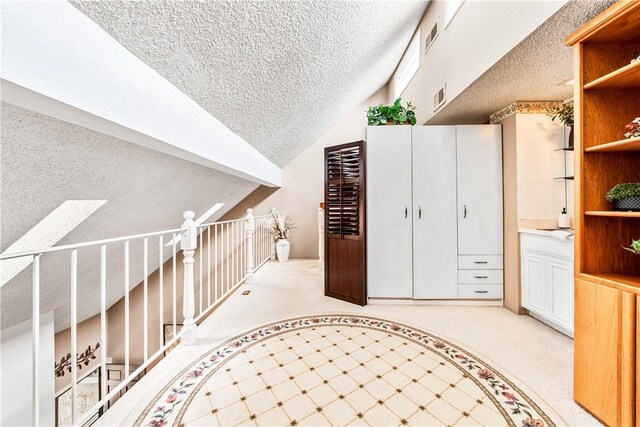 5471 E Centralia St Unit 24, Long Beach, CA 90808 - hallway with a textured ceiling, vaulted ceiling, and carpet floors