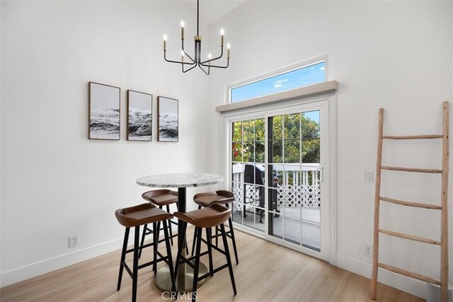 20092 Bayfront Ln Unit 206, Huntington Beach, CA 92646 - dining area with a chandelier, a towering ceiling, light wood-type flooring, and baseboards