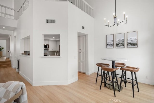 20092 Bayfront Ln Unit 206, Huntington Beach, CA 92646 - dining area featuring light wood-style floors, a high ceiling, baseboards, and a chandelier