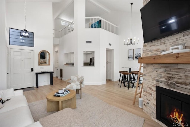 20092 Bayfront Ln Unit 206, Huntington Beach, CA 92646 - living area with wood finished floors, a chandelier, a stone fireplace, baseboards, and high vaulted ceiling