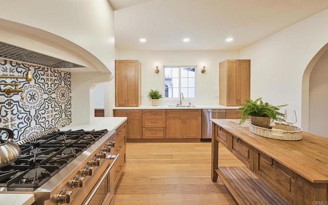 3728 Wawona Dr, San Diego, CA 92107 - kitchen featuring appliances with stainless steel finishes, arched walkways, a sink, custom range hood, and light wood finished floors