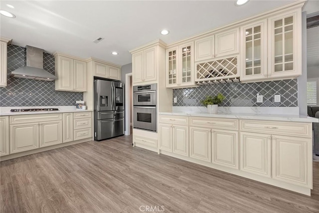17776 Buena Vista Ave, Yorba Linda, CA 92886 - kitchen featuring stainless steel appliances, cream cabinets, wall chimney exhaust hood, tasteful backsplash, and light wood-style floors