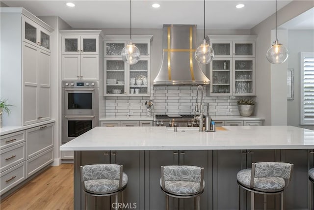 8126 Santaluz Village N, San Diego, CA 92127 - kitchen featuring double oven, exhaust hood, backsplash, light wood-style floors, and recessed lighting