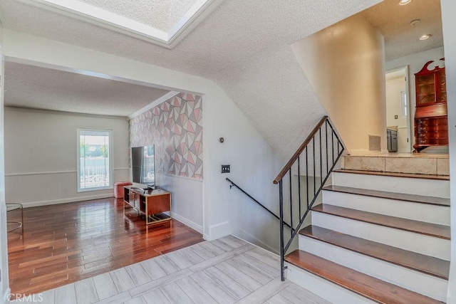 1169 Lyndhurst Dr, Riverside, CA 92507 - staircase featuring a textured ceiling, wood finished floors, a wainscoted wall, lofted ceiling, and crown molding