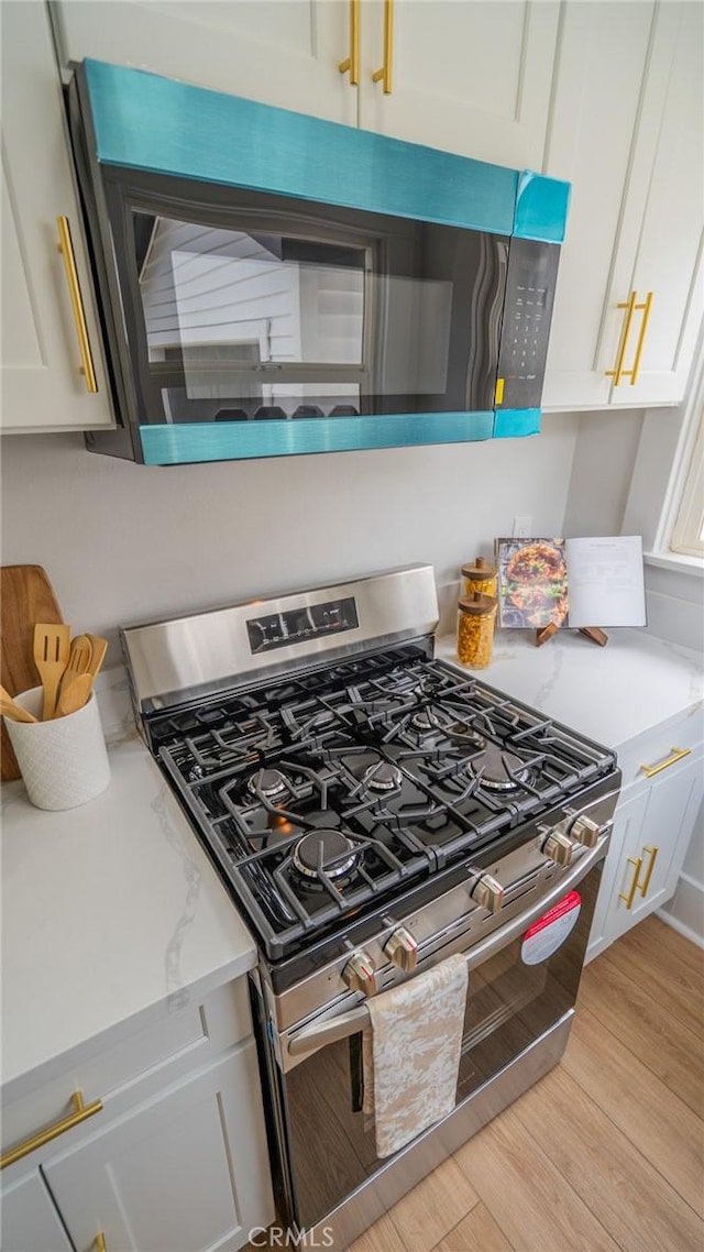 1520 Ohio Ave, Long Beach, CA 90804 - kitchen featuring appliances with stainless steel finishes, light wood-style flooring, white cabinets, and light stone countertops