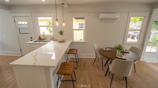 1520 Ohio Ave, Long Beach, CA 90804 - kitchen with a wall unit AC, baseboards, a kitchen breakfast bar, a sink, and light wood-type flooring
