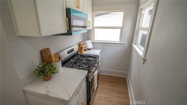 1520 Ohio Ave, Long Beach, CA 90804 - kitchen featuring stainless steel gas stove, baseboards, light wood-type flooring, light stone counters, and white cabinetry
