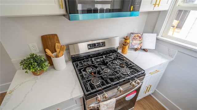 1520 Ohio Ave, Long Beach, CA 90804 - kitchen view of gas stove, white cabinets, light stone countertops, light wood finished floors, and baseboards