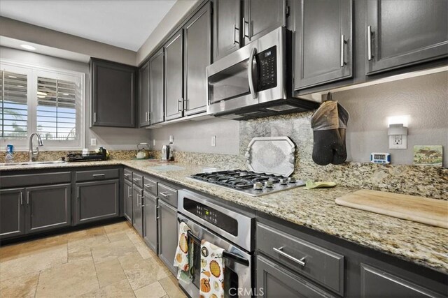 23501 Brigin Pl, Murrieta, CA 92562 - kitchen with appliances with stainless steel finishes, a sink, stone tile flooring, light stone countertops, and decorative backsplash