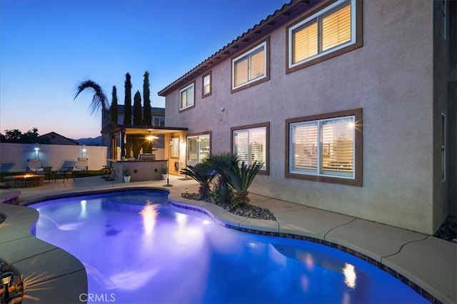 23501 Brigin Pl, Murrieta, CA 92562 - pool at dusk with a fire pit, a patio area, and an outdoor kitchen