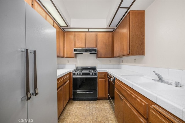 17202 Corbina Ln Unit 206, Huntington Beach, CA 92649 - kitchen with range with gas cooktop, under cabinet range hood, freestanding refrigerator, and brown cabinets