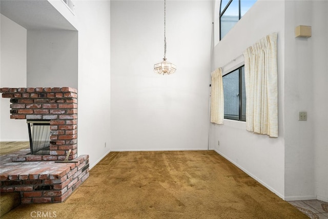 17202 Corbina Ln Unit 206, Huntington Beach, CA 92649 - unfurnished living room with carpet floors, a brick fireplace, a high ceiling, and a chandelier