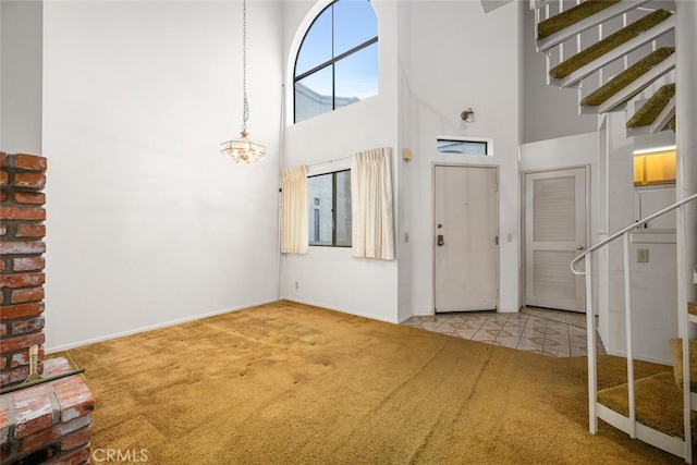 17202 Corbina Ln Unit 206, Huntington Beach, CA 92649 - foyer with carpet flooring, a towering ceiling, stairs, a chandelier, and baseboards