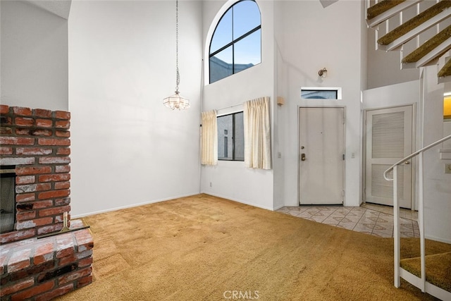 17202 Corbina Ln Unit 206, Huntington Beach, CA 92649 - tiled foyer featuring carpet, a high ceiling, stairs, a brick fireplace, and a chandelier