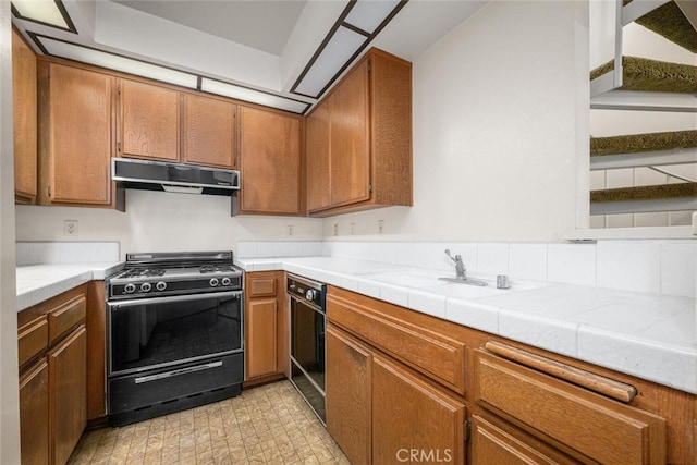 17202 Corbina Ln Unit 206, Huntington Beach, CA 92649 - kitchen featuring black appliances, under cabinet range hood, brown cabinetry, light countertops, and a sink