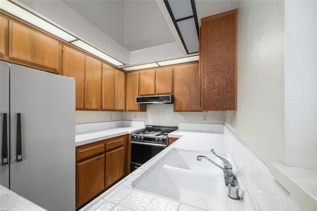 17202 Corbina Ln Unit 206, Huntington Beach, CA 92649 - kitchen featuring freestanding refrigerator, gas stove, range hood, and brown cabinets