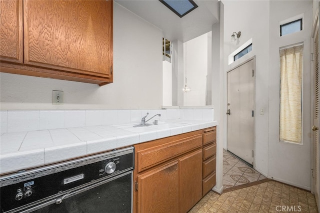 17202 Corbina Ln Unit 206, Huntington Beach, CA 92649 - kitchen featuring dishwashing machine, tile counters, and brown cabinetry