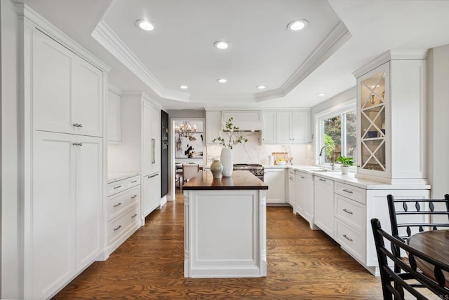 3686 Landfair Ct, San Diego, CA 92130 - kitchen with dark wood-type flooring, a raised ceiling, butcher block counters, a kitchen island, and crown molding