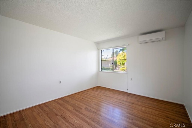 270 Avenida Sevilla Unit C, Laguna Woods, CA 92637 - spare room with a wall mounted AC, wood finished floors, baseboards, and a textured ceiling