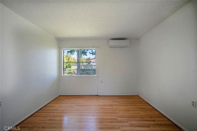 270 Avenida Sevilla Unit C, Laguna Woods, CA 92637 - spare room with a wall unit AC, light wood-type flooring, a textured ceiling, and baseboards