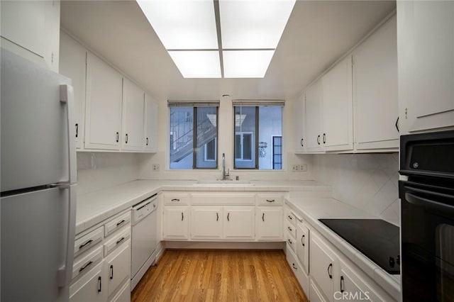 270 Avenida Sevilla Unit C, Laguna Woods, CA 92637 - kitchen with black appliances, a sink, white cabinets, light wood-type flooring, and tasteful backsplash