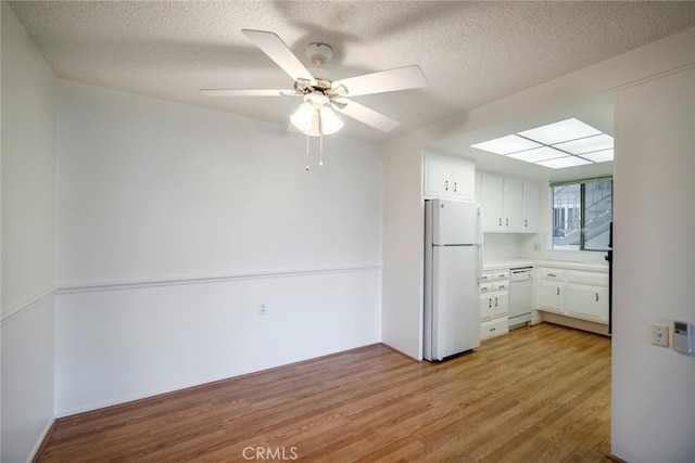 270 Avenida Sevilla Unit C, Laguna Woods, CA 92637 - kitchen featuring white appliances, light wood-style flooring, a textured ceiling, white cabinets, and ceiling fan