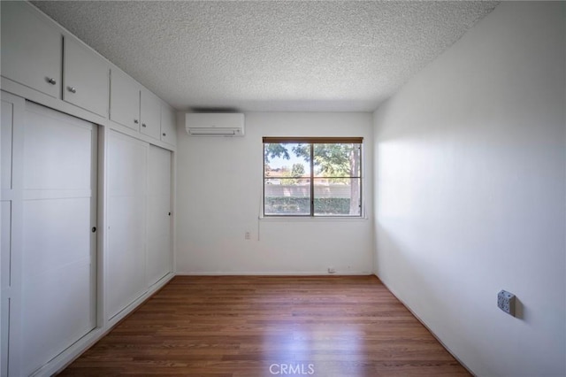 270 Avenida Sevilla Unit C, Laguna Woods, CA 92637 - unfurnished bedroom with a wall mounted AC, wood finished floors, a textured ceiling, a closet, and baseboards