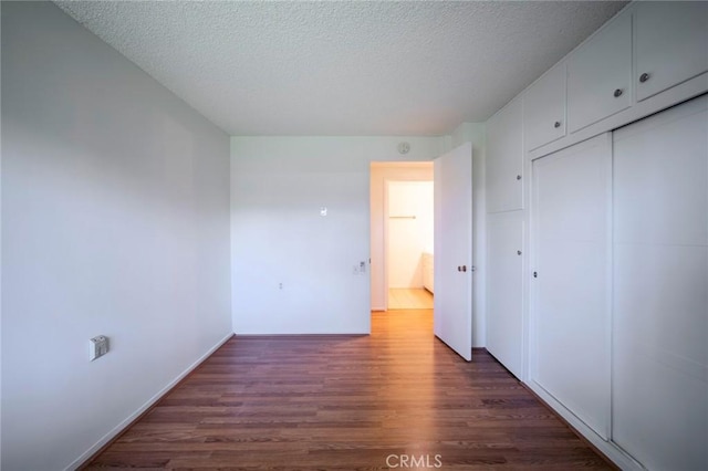 270 Avenida Sevilla Unit C, Laguna Woods, CA 92637 - unfurnished bedroom with wood finished floors, a textured ceiling, a closet, and baseboards