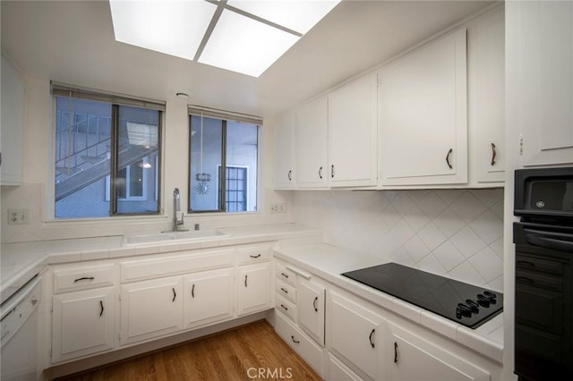 270 Avenida Sevilla Unit C, Laguna Woods, CA 92637 - kitchen featuring a sink, black appliances, white cabinets, tasteful backsplash, and tile counters