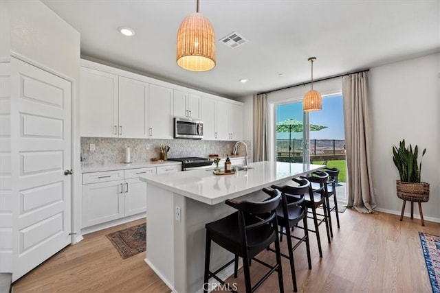 11653 Couples Ct, Beaumont, CA 92223 - kitchen with stainless steel appliances, backsplash, light wood-type flooring, white cabinetry, and light countertops