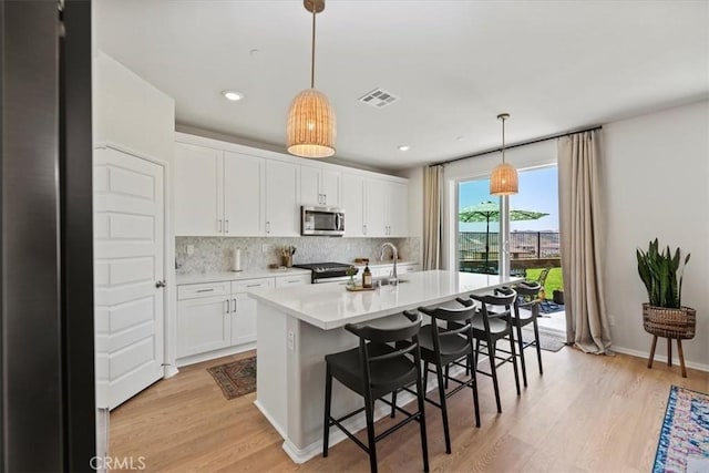 11653 Couples Ct, Beaumont, CA 92223 - kitchen with stainless steel appliances, light wood finished floors, decorative backsplash, white cabinetry, and recessed lighting