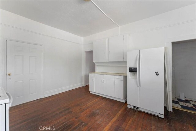 818 6th St, Corning, CA 96021 - kitchen featuring white fridge with ice dispenser, light countertops, dark wood-style floors, and white cabinets