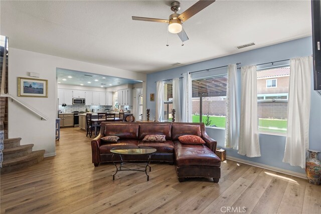 3042 San Luis Dr, Lancaster, CA 93535 - living area featuring light wood-type flooring, ceiling fan, stairs, and baseboards