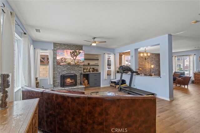 3042 San Luis Dr, Lancaster, CA 93535 - living room featuring wood finished floors, a stone fireplace, a ceiling fan, a chandelier, and baseboards