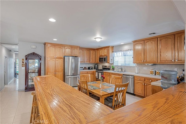 8960 Telfair Ave, Sun Valley, CA 91352 - kitchen featuring appliances with stainless steel finishes, light tile patterned floors, backsplash, butcher block countertops, and recessed lighting