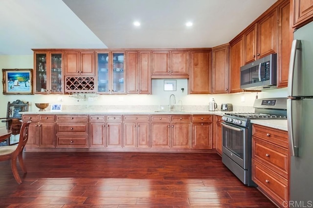 1129 La Casa, San Marcos, CA 92078 - kitchen with stainless steel appliances, brown cabinets, dark wood finished floors, recessed lighting, and glass insert cabinets
