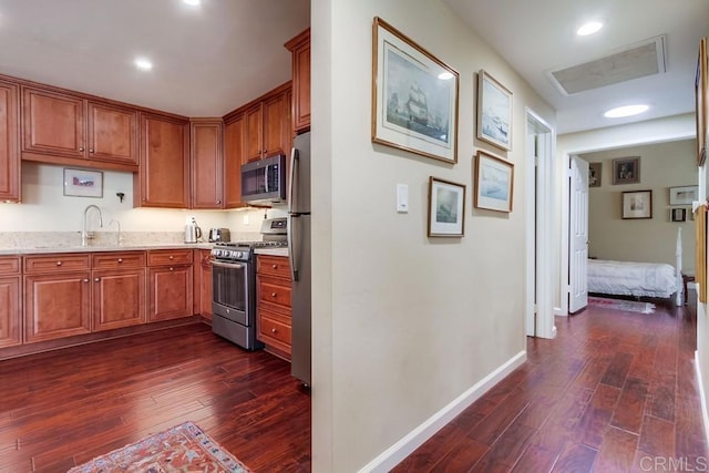1129 La Casa, San Marcos, CA 92078 - kitchen with appliances with stainless steel finishes, dark wood-style flooring, brown cabinets, and light stone countertops